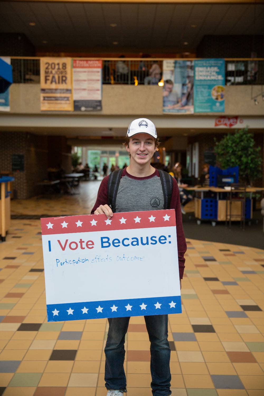 Student holding sign titled "I vote because: Participation effects outcome"